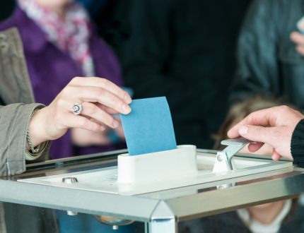 Main posant une enveloppe dans une urne pour les élections